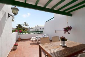 a patio with a wooden table and chairs on a balcony at Apartamento Rocas Negras in Puerto del Carmen