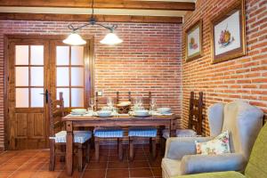 a dining room with a table and chairs and a brick wall at Las Puentes 2 in Candelario +17 photos