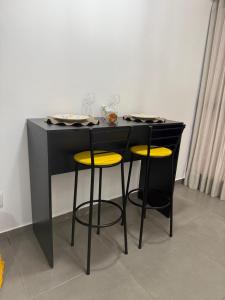 a black table with two stools with yellow seats at Residencial Loft - Studio -407 in Maceió