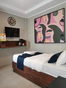 a bedroom with a bed and a tv on the wall at Townhouse Oak Grey Hotel Near Clark International Airport in Pampang