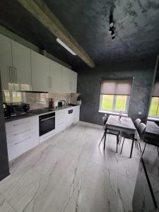 kuchnia z białymi szafkami i stołem w obiekcie Miķeļi 