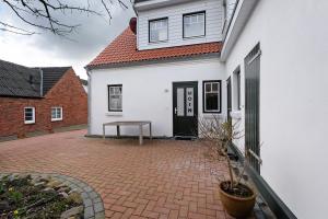 Casa blanca con patio de ladrillo en Tu Huus, en Wesselburen