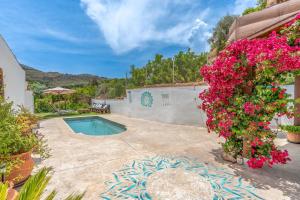 ein Haus mit einem Pool und Blumen in der Unterkunft Casa con Vistas a Sierra Nevada in Saleres