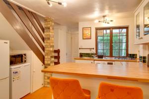 eine Küche mit einer Theke und 2 orangefarbenen Stühlen in der Unterkunft Stylish Victorian Terrace in Central Cambridge Pass the Keys in Cambridge