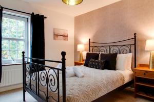 ein Schlafzimmer mit einem schwarzen Bett und einem Fenster in der Unterkunft Stylish Victorian Terrace in Central Cambridge Pass the Keys in Cambridge