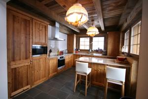 a large kitchen with wooden cabinets and white chairs at Alouette in Grimentz