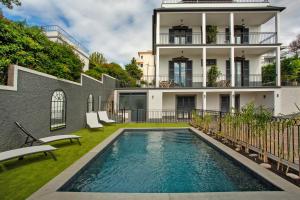 a house with a swimming pool in front of a building at Vila Francisco in Funchal