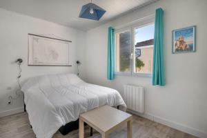 ein Schlafzimmer mit einem Bett und einem Tisch und einem Fenster in der Unterkunft Jacuzzi Maison pour 11 au calme plage a 500m in Le Cormier