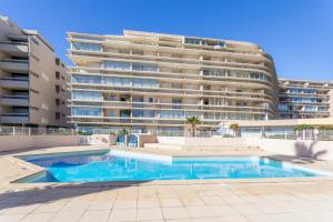 a swimming pool in front of a large building at Studio vue mer in Canet-en-Roussillon