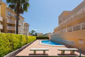 オリーバにあるPar3のスイミングプールとベンチ2つ付きの建物