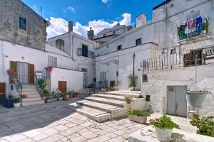 a courtyard of white buildings with stairs and potted plants at Le Antiche Mansioni 1 in Monte SantʼAngelo
