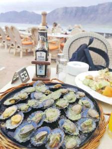 Ein Teller Austern auf einem Tisch mit einer Flasche in der Unterkunft Casa Rafa in Famara