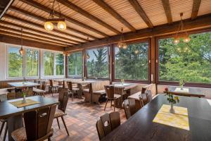 un restaurant avec des tables, des chaises et des fenêtres dans l'établissement Naturerlebnishaus Gaistal, à Bad Herrenalb