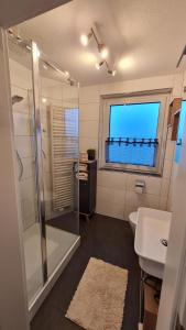 a bathroom with a shower and a sink and a window at Ferienwohnung Helfensteinblick in Calden