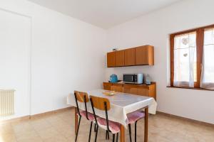 eine Küche mit einem Tisch mit Stühlen und einer Mikrowelle in der Unterkunft Appartamento Villanova in Villanova Strisaili + 23 Fotos