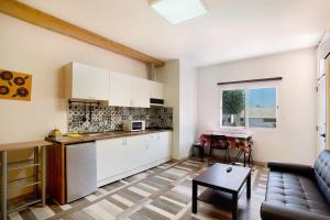 a kitchen with white cabinets and a living room at Apartamento C para 2 en Vecindario in Vecindario