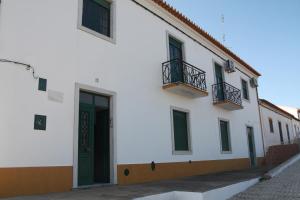 een wit gebouw met een groene deur en ramen bij Casa do Sossego in Safara