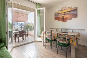 a dining room with a table and chairs and a balcony at Tirreno apartment in Alghero