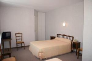 ein Schlafzimmer mit einem Bett, einem Stuhl und einem TV in der Unterkunft Hôtel du Marché in Beauvoir-sur-Mer