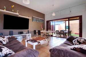 Una sala de estar con un sofá y un televisor. en Villa Dayely, en Corralejo