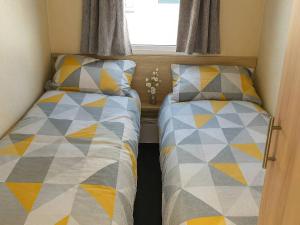 two beds sitting next to each other in a bedroom at Golden Gate Holiday Centre - Holiday Accommodation 19059 in Kinmel Bay
