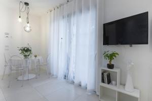 a white living room with a table and a television at Ricky's Luxury Apartment in Misano Adriatico