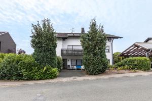 a white house with trees in front of a street at Ferienwohnung Neuenrade in Neuenrade