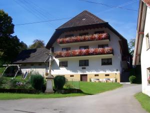 a white building with lots of red flowers on it at Kuryhof in Simonswald