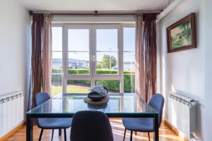 ein Esszimmer mit einem Glastisch und Stühlen sowie einem Fenster in der Unterkunft Apartamento San Juan Cuchía in Cuchia