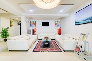 a living room with white furniture and a large screen at Hotel O Skyland in Ahmedabad +23 photos