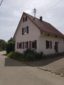a white house with red shutters on a street at Ferienhäusle vom Hof Chirphendorf in Steinheim