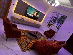 a living room with a tv and chairs and a table at DXB Residence in Lekki
