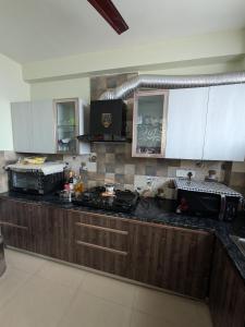 a kitchen with white cabinets and a black counter top at GURUGRAM CENTRAL NEAR To AIRPORT in Gumgaon