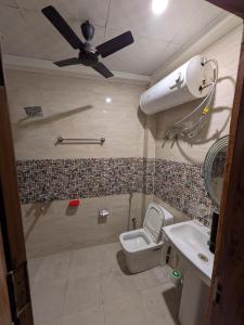 a bathroom with a toilet and a sink and a ceiling fan at GURUGRAM CENTRAL NEAR To AIRPORT in Gumgaon +13 photos
