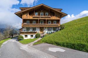 a large wooden house on a hill with a road at Unterlehenhof N in Zell am Ziller