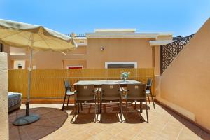 a table and chairs on a balcony with an umbrella at Casa Miramar in Caleta De Fuste