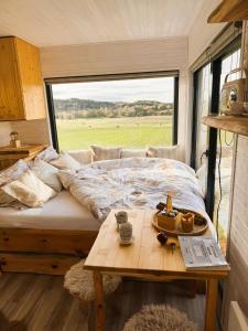 un lit et une table dans une pièce avec une fenêtre dans l'établissement Luxusní chaty v Ráji & Romantický posed s výhledem na Trosky, à Újezd pod Troskami
