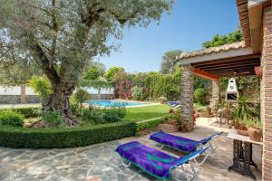 a patio with two purple lounge chairs and a tree at Casa Buganvilla by Vintage Travel in Órgiva