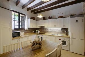 a kitchen with white cabinets and a wooden table at Can Teresa in Capdepera