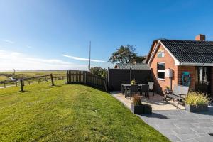 a small red brick house with a grass yard at Ferienwohnung Hafenblick in Oland