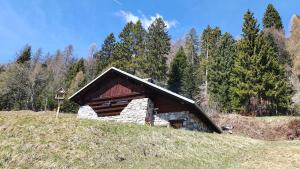 a small building on a hill in a field at Baita casapendola in Marter di Roncegno