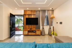 a living room with a television on a wooden entertainment center at The Garden Retreat by StayJadePool2BHKLawn in Berikai