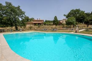 a large blue swimming pool with a house in the background at Ginepro Poderone in Grosseto