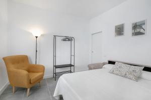 a white bedroom with a bed and a chair at El Ramonal Home in Candelaria