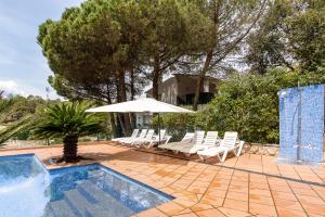 une piscine avec des chaises et un parasol dans l'établissement Villa Yulia, à Vidreres