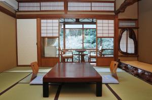 een kamer met een tafel en stoelen en een raam bij Iwaso in Miyajima