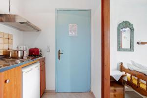a kitchen with a blue door in a room at Areti Orfeas Budget Studio in Vasilikos