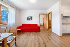 ラグンドにあるFröhlichhof Wohnung Pergolaの赤いソファとテーブルのあるリビングルーム +21枚の写真
