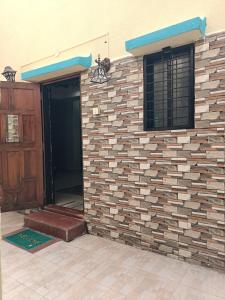 un mur de briques avec une porte et une fenêtre dans l'établissement Near Swargate Vrundavan 2 BHK bungalow, à Pune