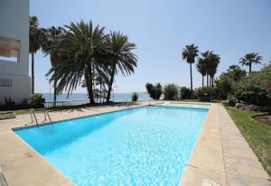 a large swimming pool with palm trees and the ocean at Apartment Boulevard 205 in Estepona +18 photos